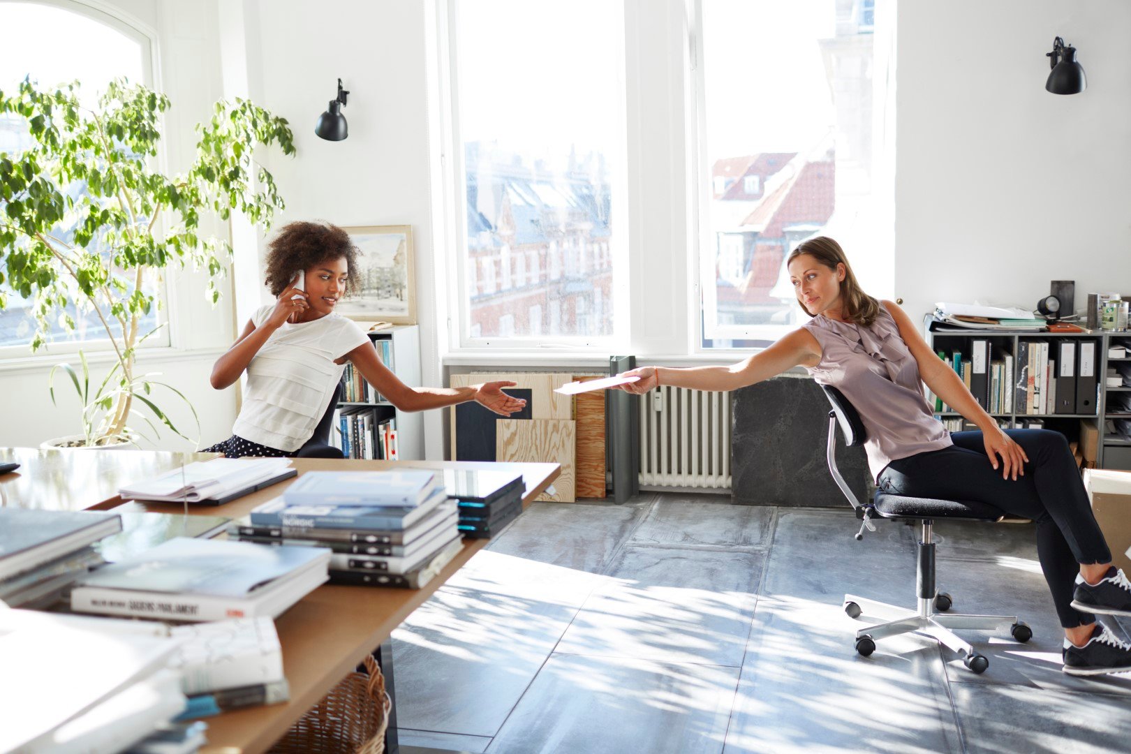 woman handing a report to another woman talking on the phone.jpg